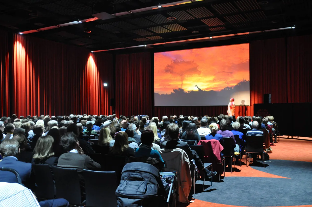 Publikum vor der großen Leinwand bei einer Abenteuer-Weltumrundung-Show